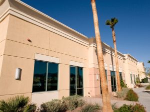 Modern commercial space with beige exterior walls using the best cladding materials, complemented by desert landscaping.