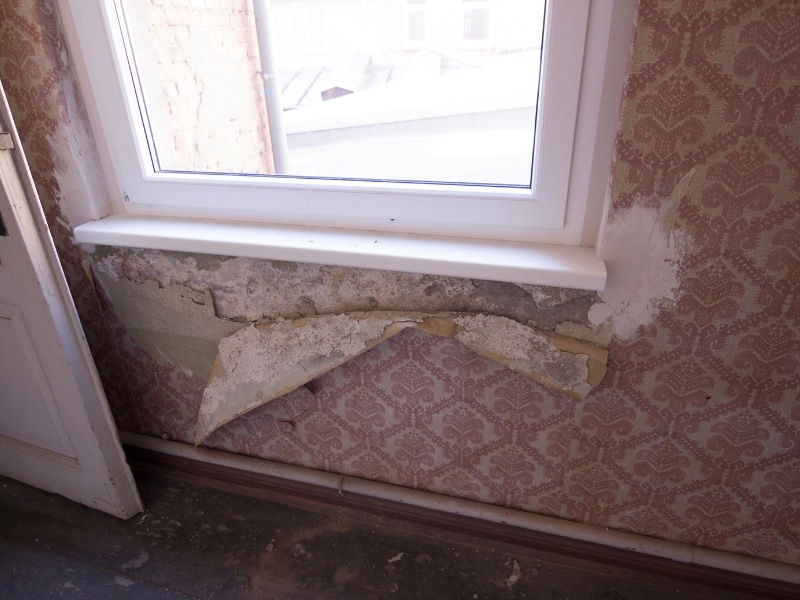 Damaged wall showing peeling layers before acrylic render application repair