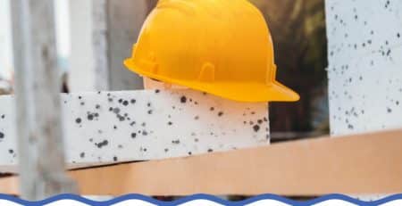 Yellow hard hat resting on rendered polystyrene cladding at a construction site