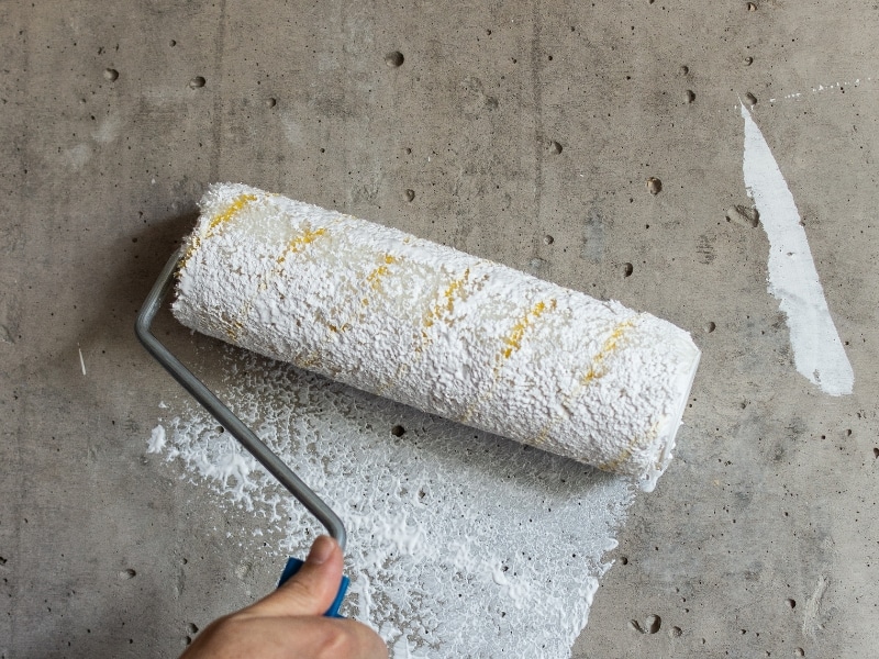 applying white concrete texture coating using a roller on bare wall