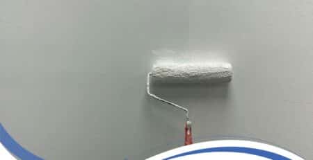 Worker applying exterior textured wall coatings with roller for smooth, durable wall protection.