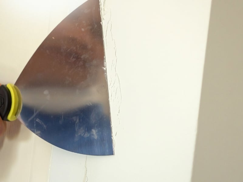 Filling a wall crack with a scraper using Wall Crack Repair Methods.